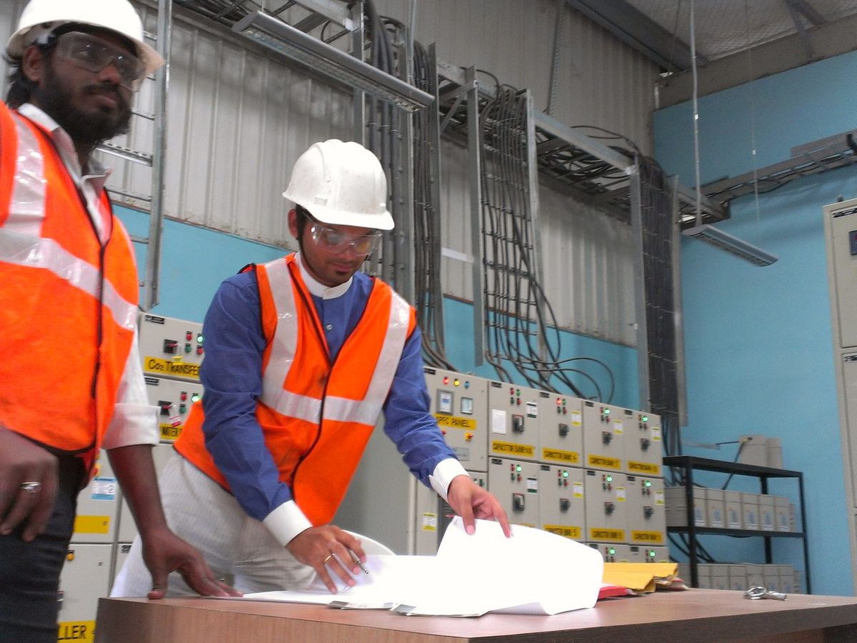 Two VB engineers reviewing drawings beside a motor control centre