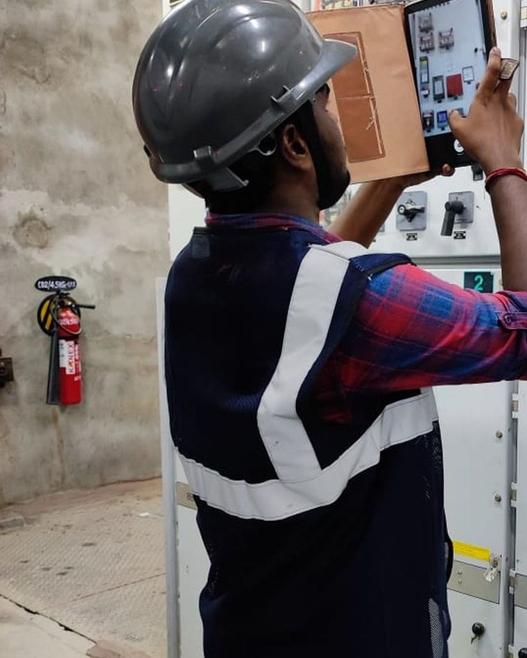 A VB engineer photographing switchgear nameplate data on a tablet during a walkdown