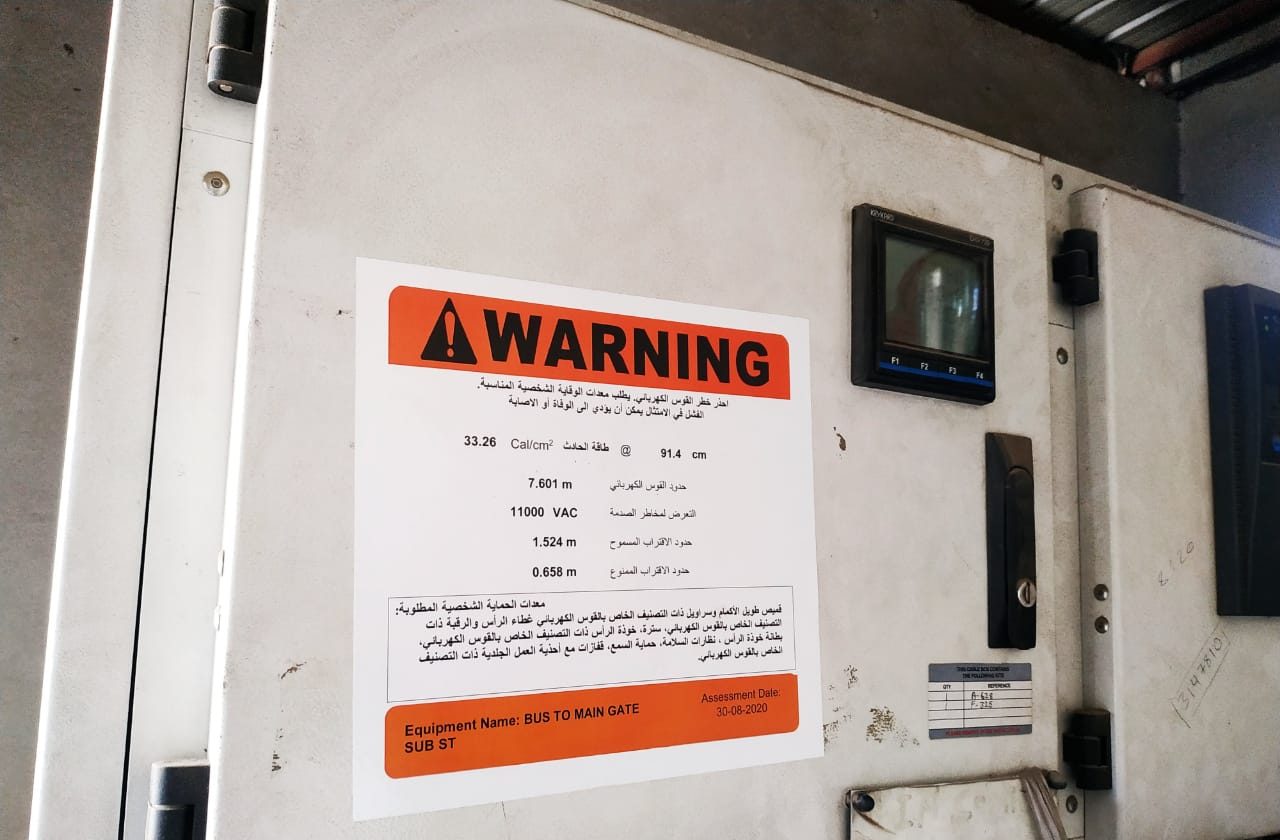 VB arc flash warning label in Arabic installed on an 11 kV panel, showing 33.26 cal/cm² at 91.4 cm, arc flash boundary 7.601 m and assessment date