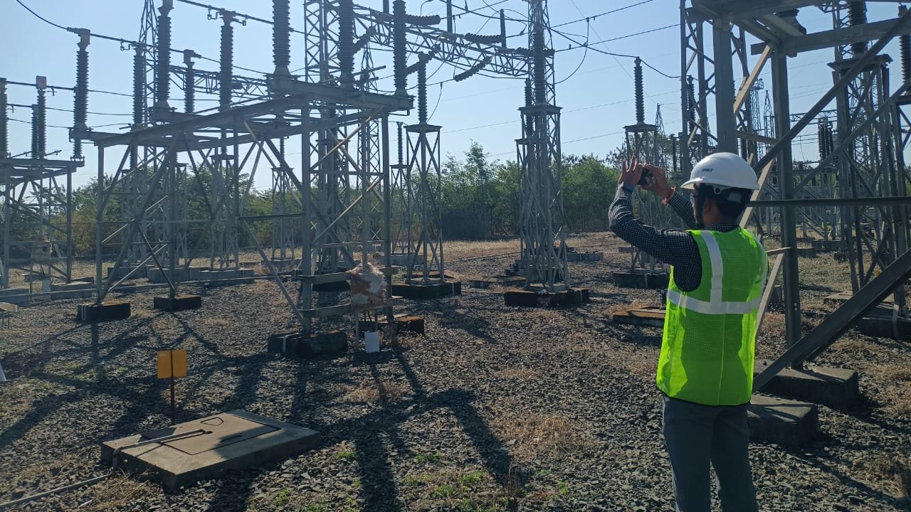 VB engineer in hi-vis and hard hat surveying an outdoor substation bay