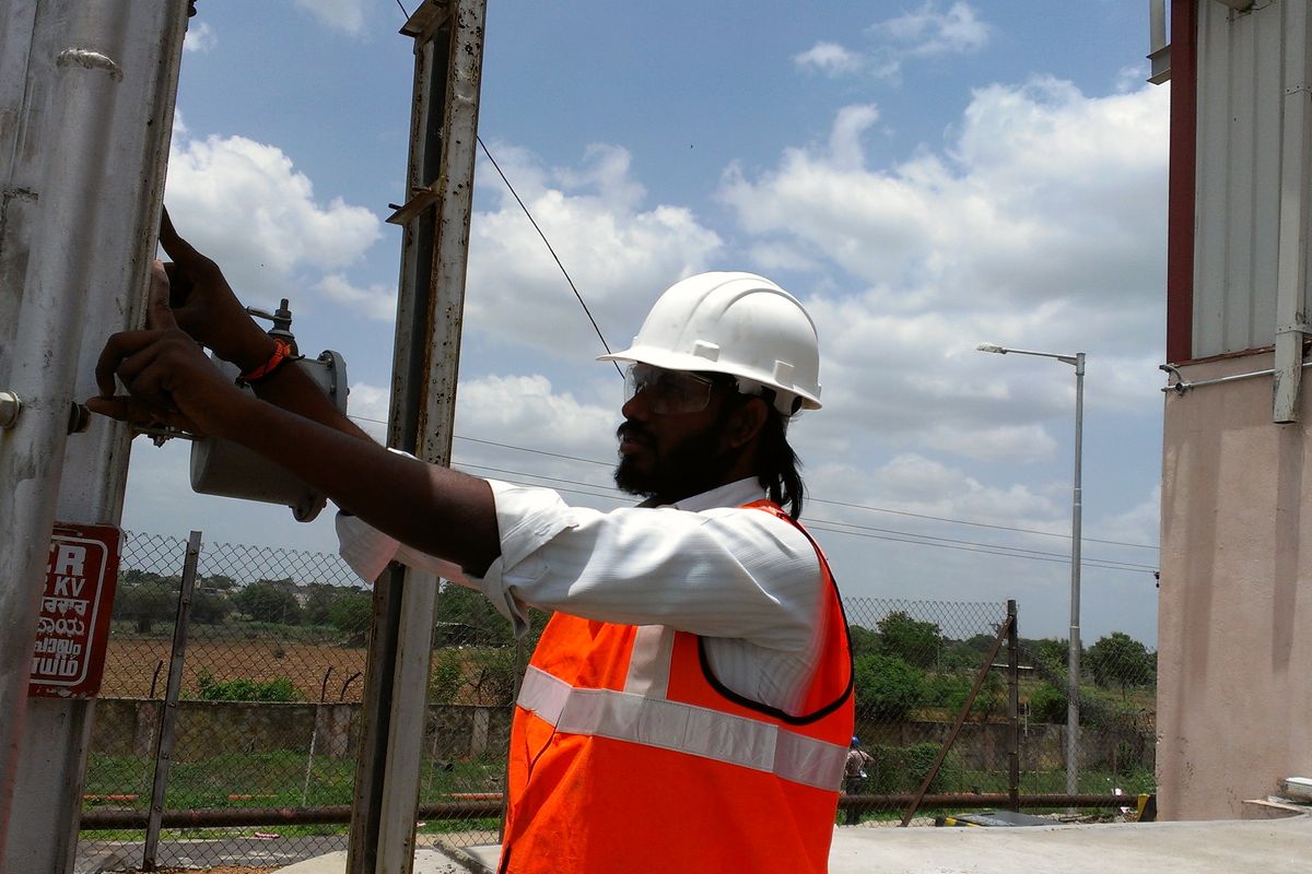 VB engineer in hard hat and hi-vis checking a steel structure and its conductor fixings at an outdoor substation
