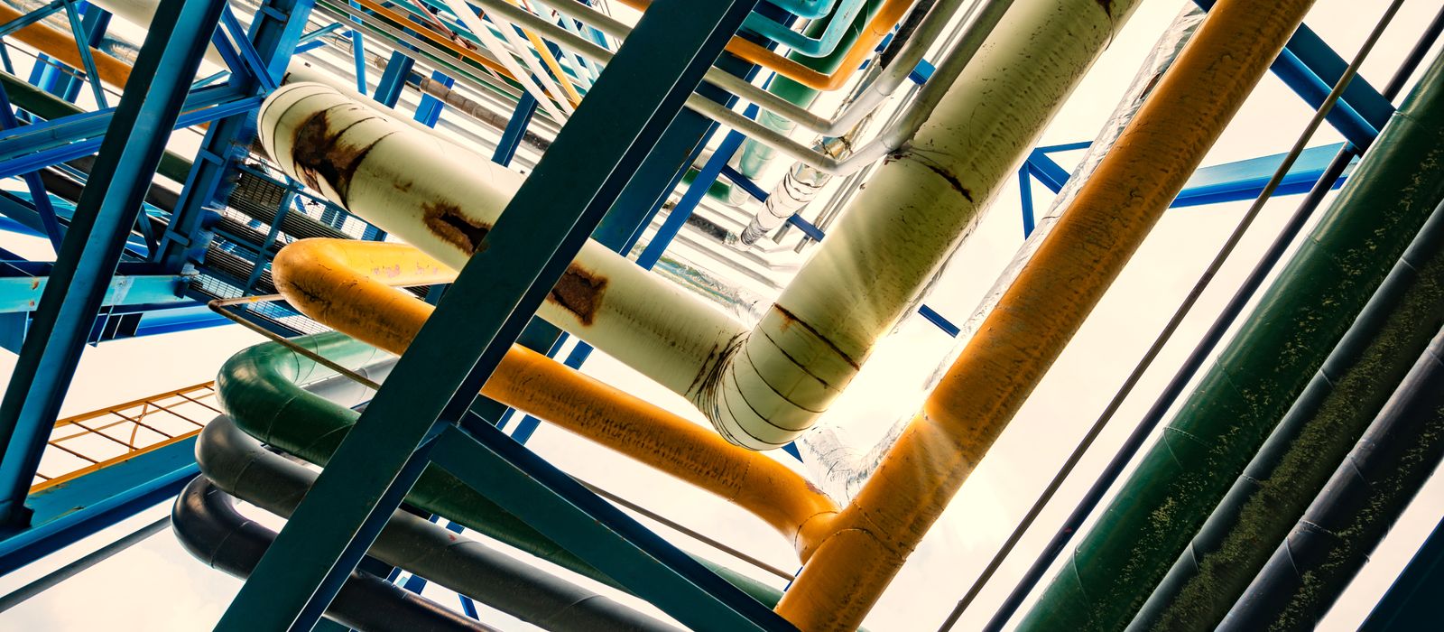 Colour-coded industrial piping and steel structure seen from below