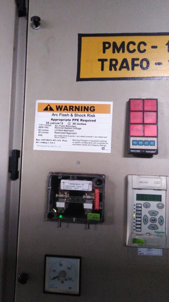 VB engineered arc flash WARNING label installed on PMCC-1 TRAFO-1 panel alongside MICOM protection relay · the deliverable outcome of the VB Arc360 program