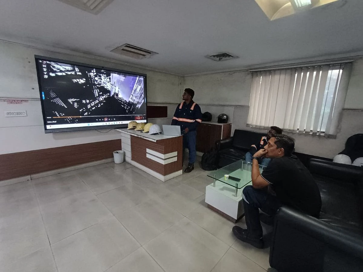 VB engineer presenting Arc Flash Safety 3D Animated Training Video on large screen to workers seated with helmets on table