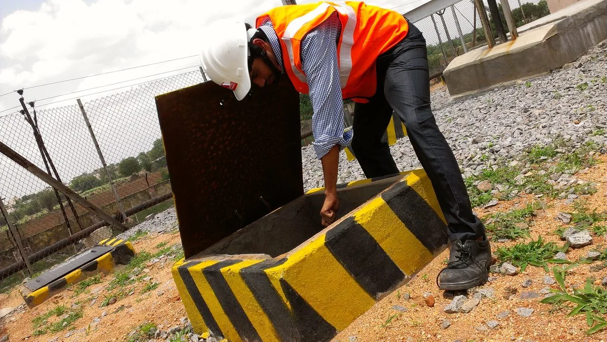 Yellow and black tiger stripe arc flash boundary painted on the cable pit walls at an outdoor 33 kV substation · the physical approach boundary called out on the VB engineered label · real field photo