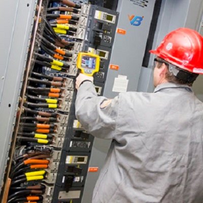 Engineer in a hard hat scanning an energised distribution board with a hand-held thermal imager